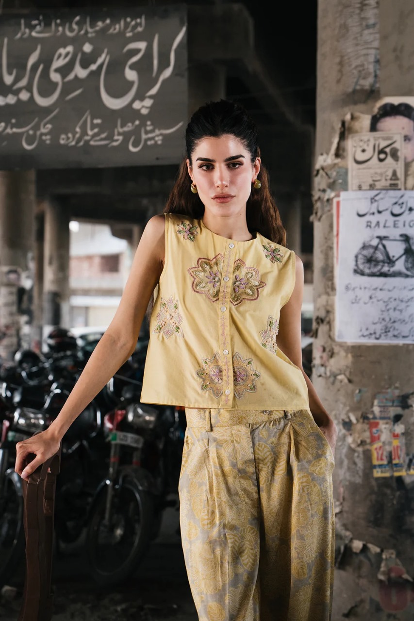 Model wearing sleeveless yellow kurti with floral embroidery